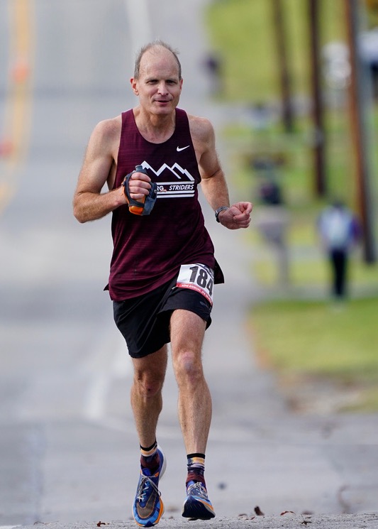 Runner holding a handheld water bottle on a road.